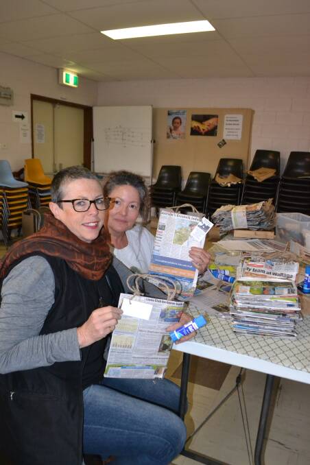 BAG LADIES: Mandy Wheatley and Lorraine Schmaman working at creating more recycled newspaper bags at the Narooma Anglican church. 