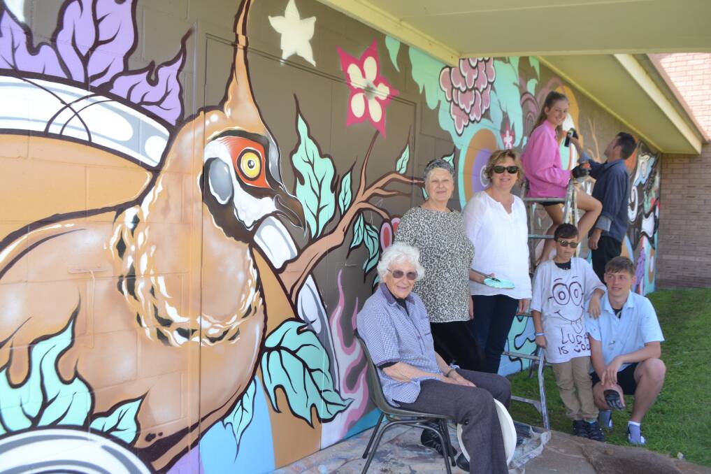 FOUR GENERATIONS: 90-year-old Mina Watt at the Anglican Church mural with her daughters Chris and Meredith, great grandchildren Harry, Anna and Luca and grandson Tim “Phibs” de Haan, a world renowned street artist. 