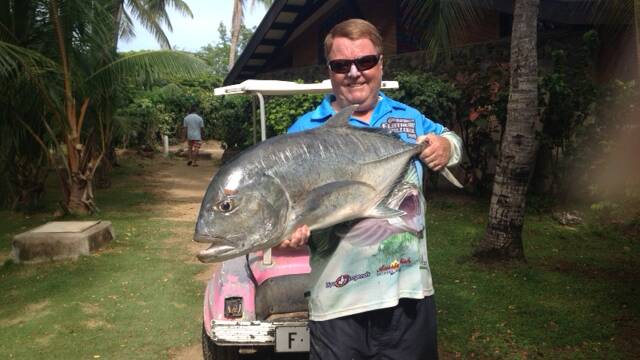 GIANT TREVALLY: Narooma Sport and Game Fishing Club president Les Waldock with the giant trevally he caught off of a beach at Plantation Island, Fiji. 
