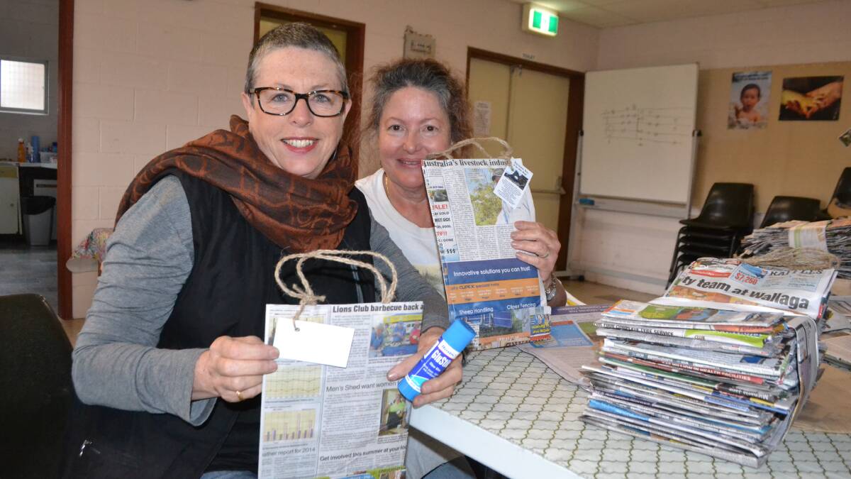 BAG LADIES: Mandy Wheatley and Lorraine Schmaman working at creating more recycled newspaper bags at the Narooma Anglican church.  