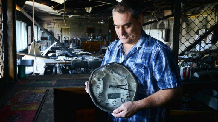 Wasleys Bowling Club secretary Brad McDougall holds a clock frozen in time by the fire north of Adelaide. Photo: Brenton Edwards