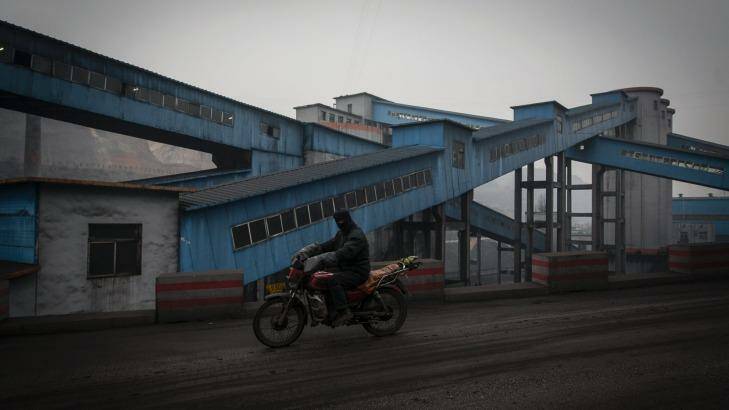 A worker rides a bike through the Xinwu Coal Mine near Liulin, Shanxi Province. China is burning less coal in line with its emissions targets. Photo: Qilai Shen