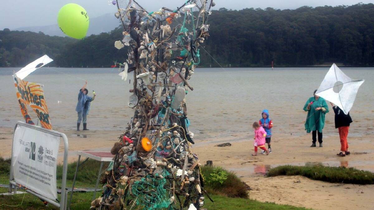 WHALE TAIL: Beach kite flying in gusty rain was tricky but enjoyable for those who gave it a go.  The Whale Tail wire sculpture was decorated by High school students with flotsam collected from local beaches. Photo by Rosy Williams 