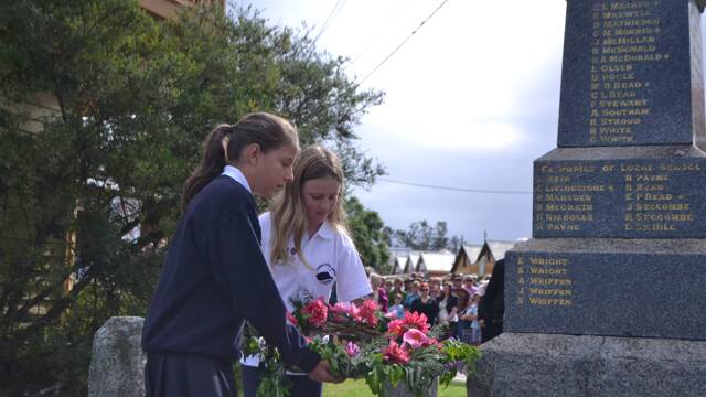 STUDENT WREATH: Central Tilba Area School students Libby Cunningham and Ruby Christmass lay a wreath at the Tilba War Memorial on ANZAC Day.