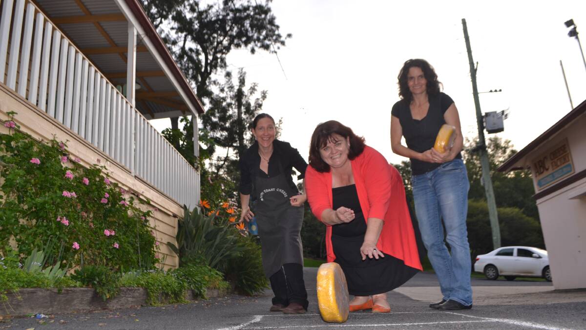 CHEESE ROLLERS: Tilba Festival organising committee member Christine Montague demonstrates the cheese rolling flanked by Zoe Cooper and Erica Dibden from the ABC Cheese Factory. 