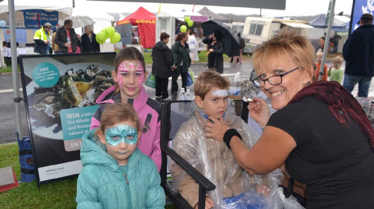 FACE PAINTING: At the ActewAGL stall at the Narooma Oyster Festival are Olivia, Georgia and Tom Ronchi of Melbourne with face painter Michele Heaton. Photo Stan Gorton