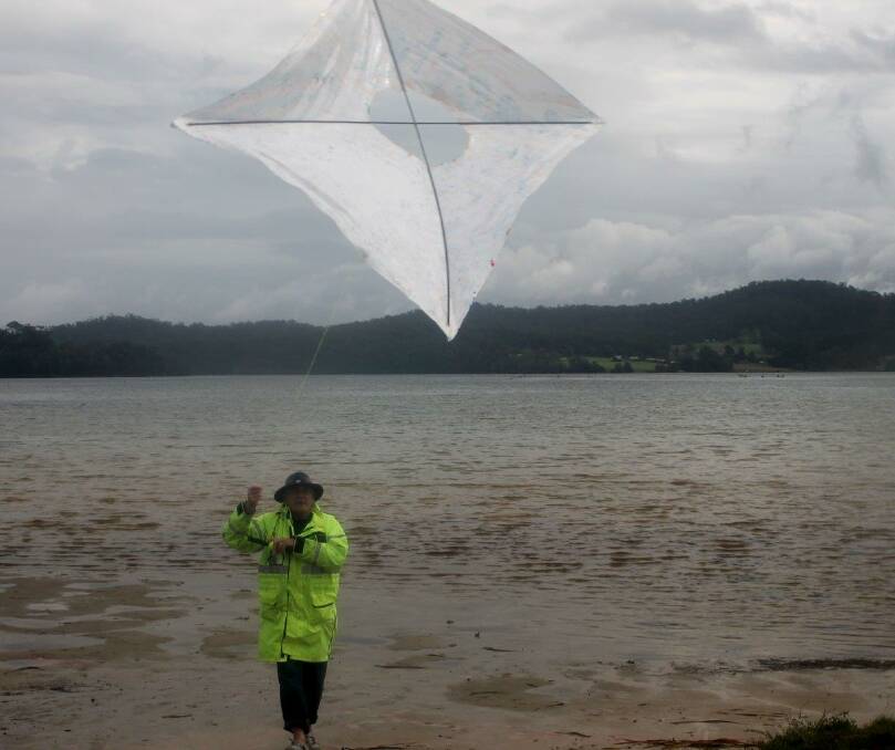 KITER: Volunteer Tony Pye skilfully nurses his kite into rainy skies on Wagonga. Photo by Rosy Williams  