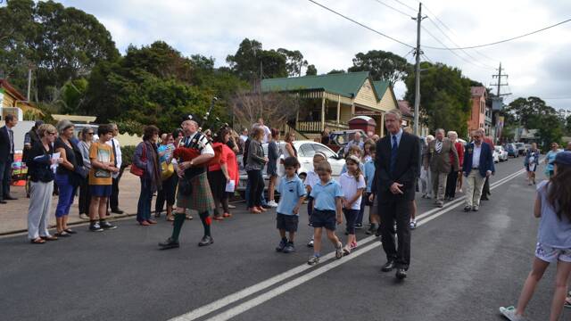 THE MARCH: Lone piper Peter McIntosh and the students and principal John Carter from Central Tilba Area School lead the Tilba ANZAC Day march.