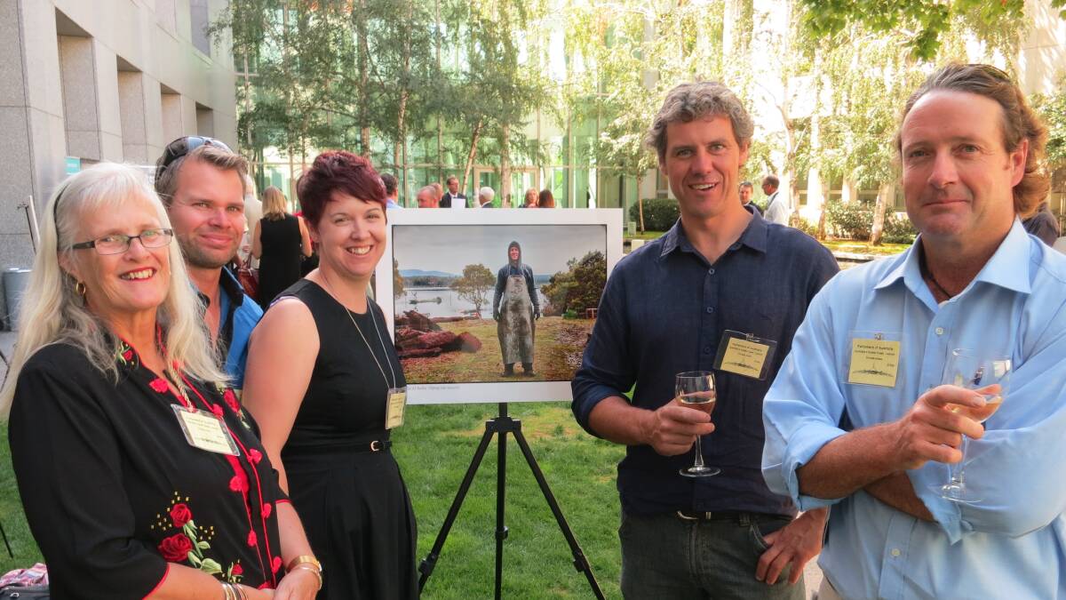 SOUTH GROWERS: Local oyster growers at the launch in Canberra were Anne, left, Andrew and Stacey Loftus from Wonboyn, Greg Carton from Pambula and Brett Weingarth of Merimbula. They are standing with the Heide Smith photograph in the exhibition of fellow oyster farmer Paul Emmanuel of Wapengo. 