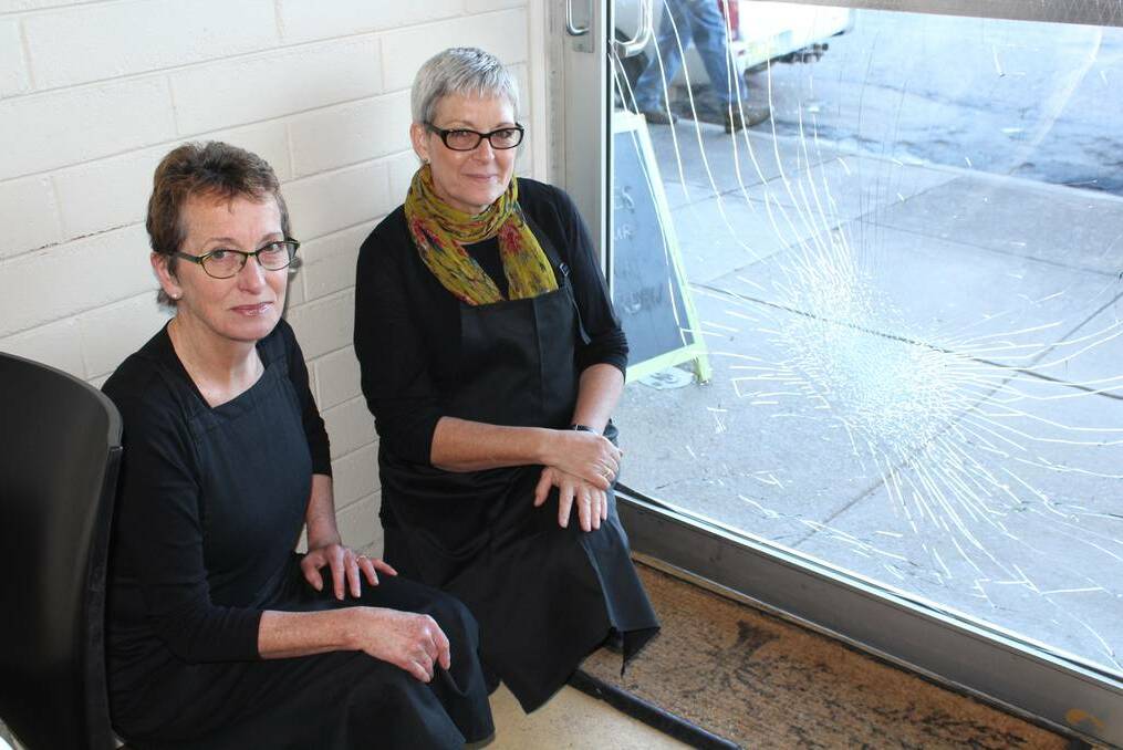 Karen Lott and Sue Flannery crouch near the front door of Sprout Cafe. The glass was damaged by a blow from the pavement, but incredibly the glass didn’t shatter. 