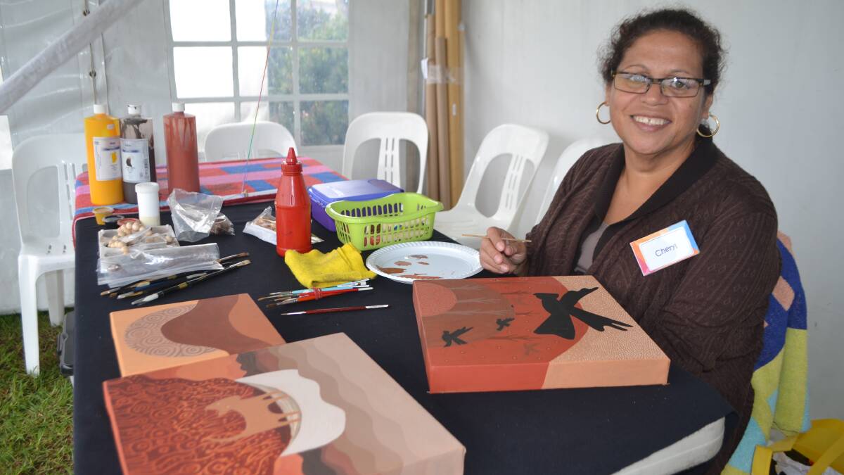 INDIGENOUS ART: Narooma indigenous artist Cheryl Davison shelters from the rain and works on her art at the Narooma Oyster Festival. Photo Stan Gorton 