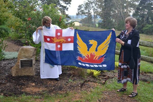 THE UNVEILING: The Reverend Carol Wagner unveils the Bodalla Time Capsule plaque that was covered with the Bodalla flag, watched by president of the Bodalla 150-year-committee president Kath Crapp.