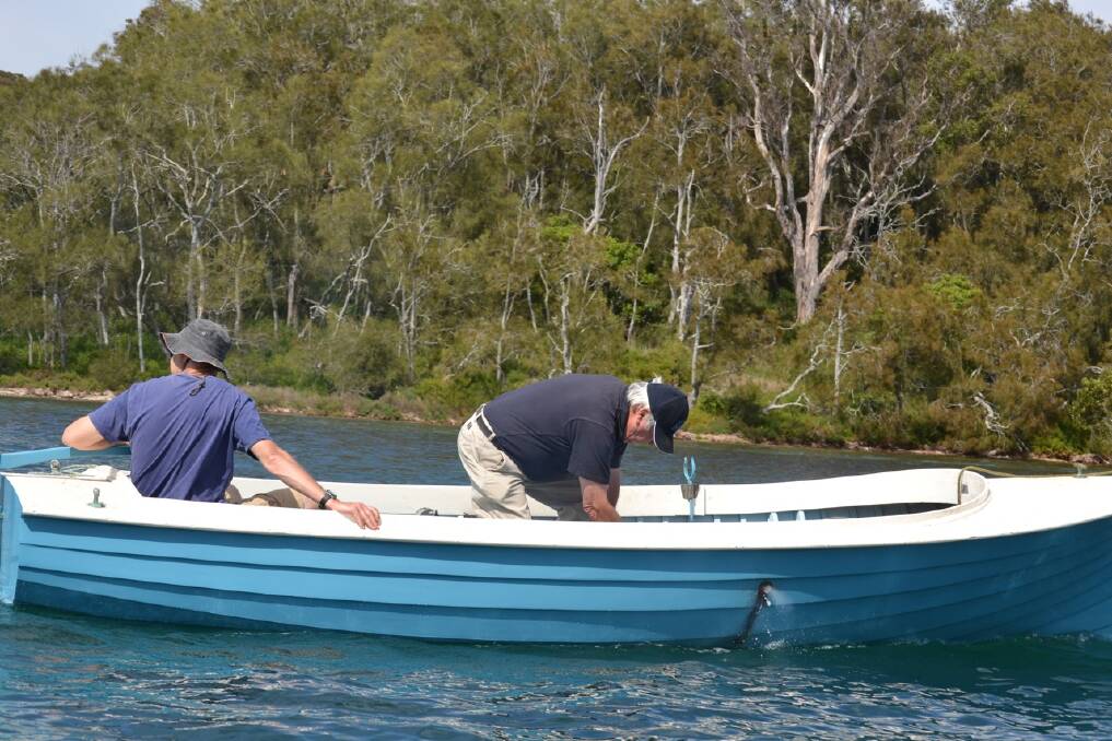 MOTOR WORK: Traditional boat motors can be temperamental and here Narooma’s John Glover works mid channel on the engine of his boat Goodrabigbee.