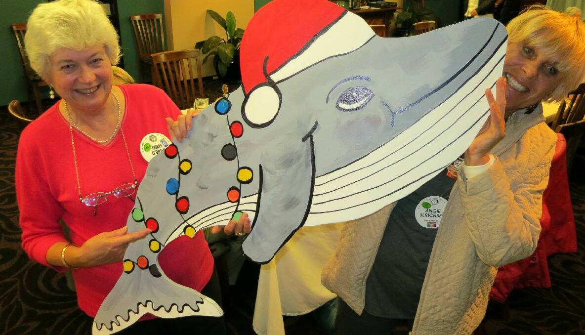 CHRISTMAS SPIRIT: Narooma Rotarians Chris O’Brien and Angie Ulrichsen are taking orders for Narooma’s Christmas whales and are pictured holding one the smaller whales available. 