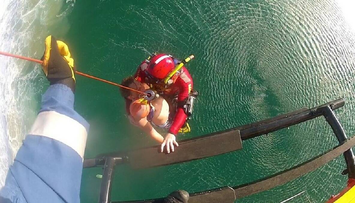 UPLIFTING: Westpac Life Saver Rescue helicopter crew officer Luke Ashford and the exhausted young surfer are winched up out of the massive surf off Narooma bar. 