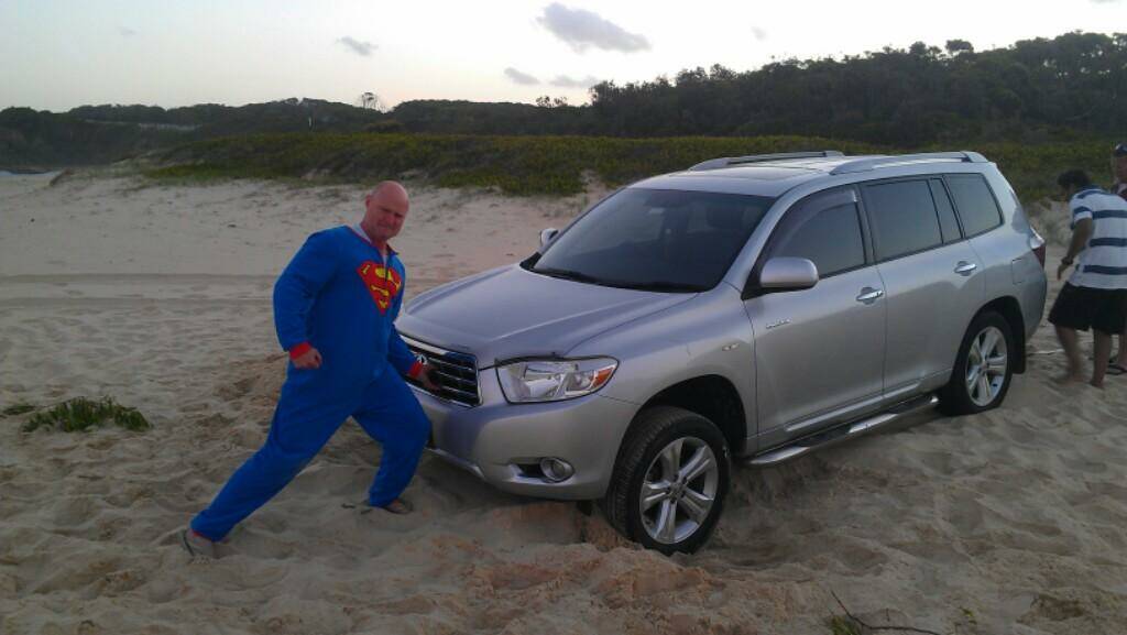 TO THE RESCUE: Not even a helpful bystander dressed as Superman could budge this bogged car that the driver thought he would take for a cruise on Narooma’s main beach on Sunday evening.