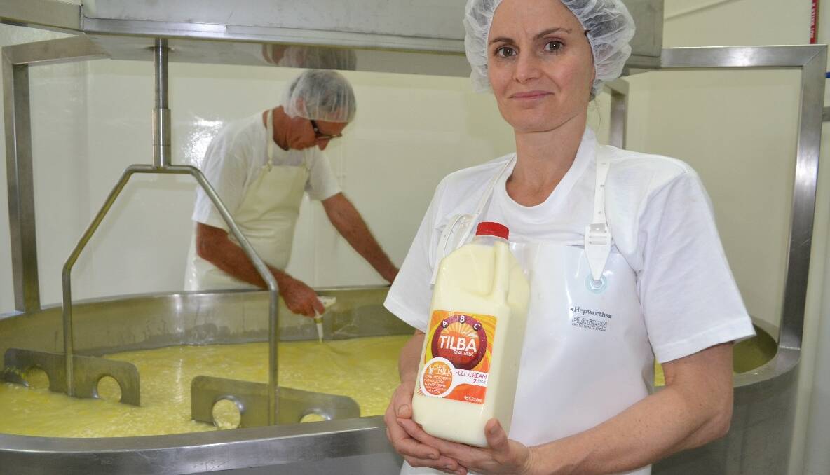 NEW MILK: Dairy farmer and now dairy-product producer Erica Dibden with a bottle of her new ABC Tilba Milk while master cheese maker Geoff Southam works on a batch of Havarti cheese in the background. 