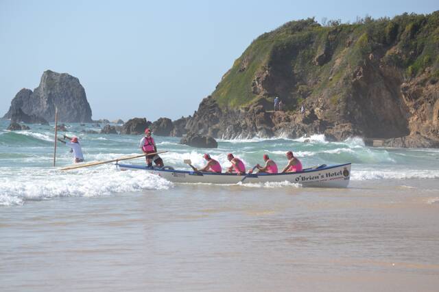 SURF ACTION: One of Narooma SLSC surfboat teams on the beach with Glasshouse Rocks in the background. Photo by Stan Gorton – Narooma News 