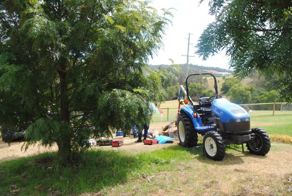 TRACTOR ACCIDENT: Police and paramedics recover the injured man from alongside the tractor and auger where he was injured during a fencing project. 