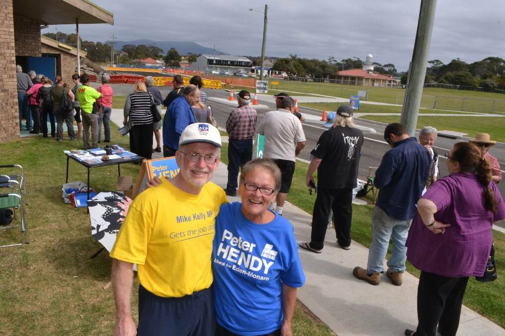 NAROOMA PRE-POLL: Proving the political parties can get along with respect, at least at the local levels, are pamphleteers Jim Bright for Labor and Maggie Havu for the Liberals at the Narooma pre-polling station on Friday. Notice the long line with reports of only one election official on duty and also the road works in the background that has caused a bit of inconvenience for voters in Narooma.