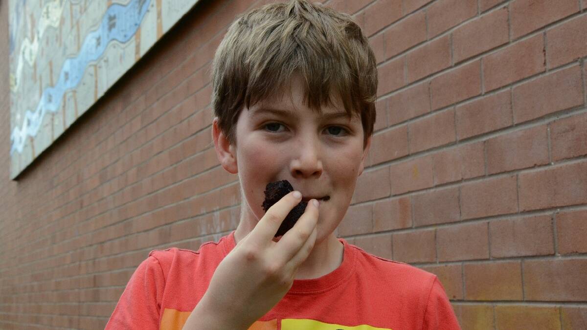 Moruya Head’s Ben Risk tucks in to some chocolate cake from the Moruya Public School cake stall.