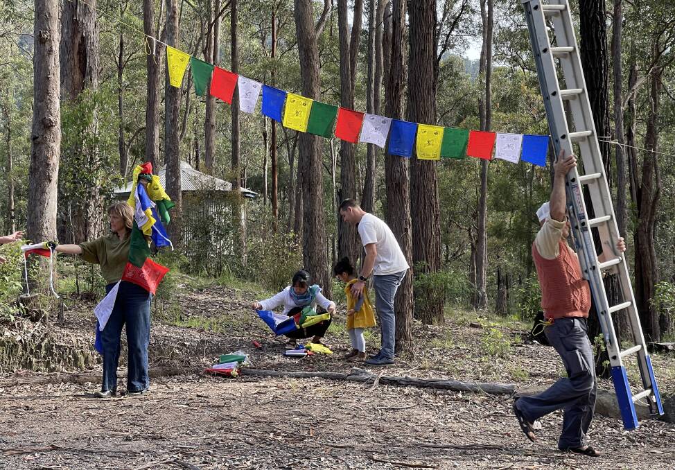 People get together to hang prayer flags in the trees at the Tilba Buddhist Centre.