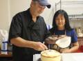 Dave and Aw Baker icing a cheesecake in their new Batemans Bay kitchen.
