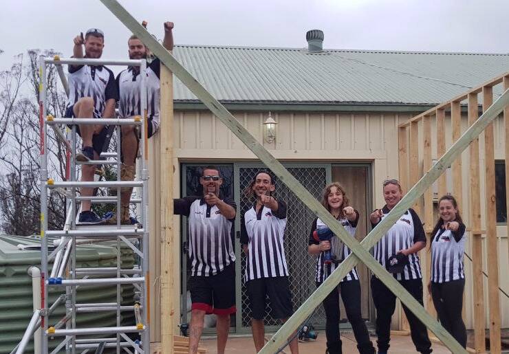 David Crooke and the bAy-TEAM wearing donated football jerseys while constructing cabins in the aftermath of the Black Summer Bushfires Photograph: supplied