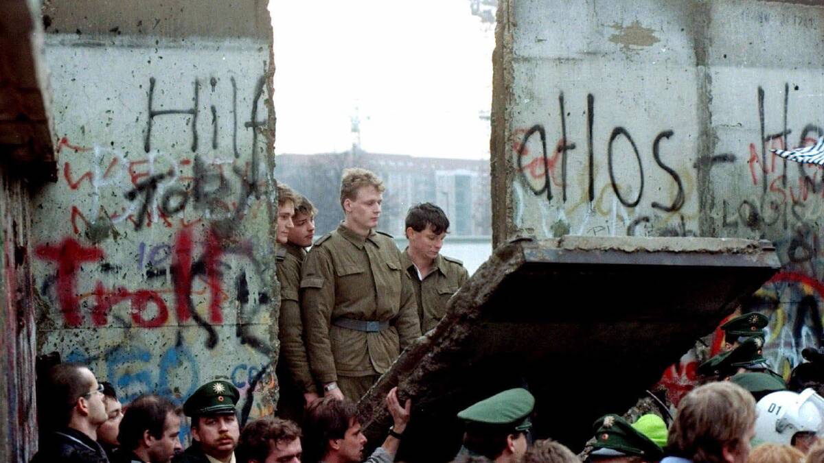 East German border guards look through a hole in the Berlin Wall after demonstrators pulled down the segment at Brandenburg Gate in Berlin. Picture by AP Photo/Lionel Cironneau East German border guards look through a hole in the Berlin Wall after demonstrators pulled down the segment at Brandenburg Gate in Berlin. Picture by AP Photo/Lionel Cironneau
