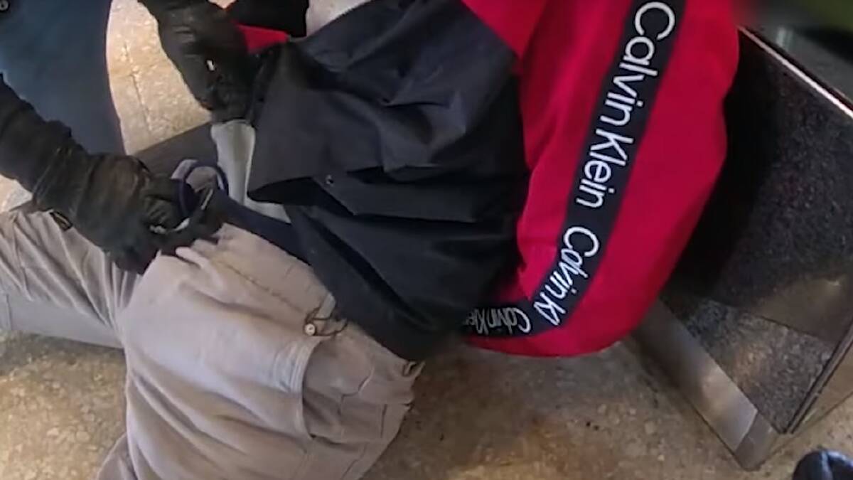 Police pull an allegedly stolen item from a man's pants in an ACT shopping centre. Picture via ACT Police