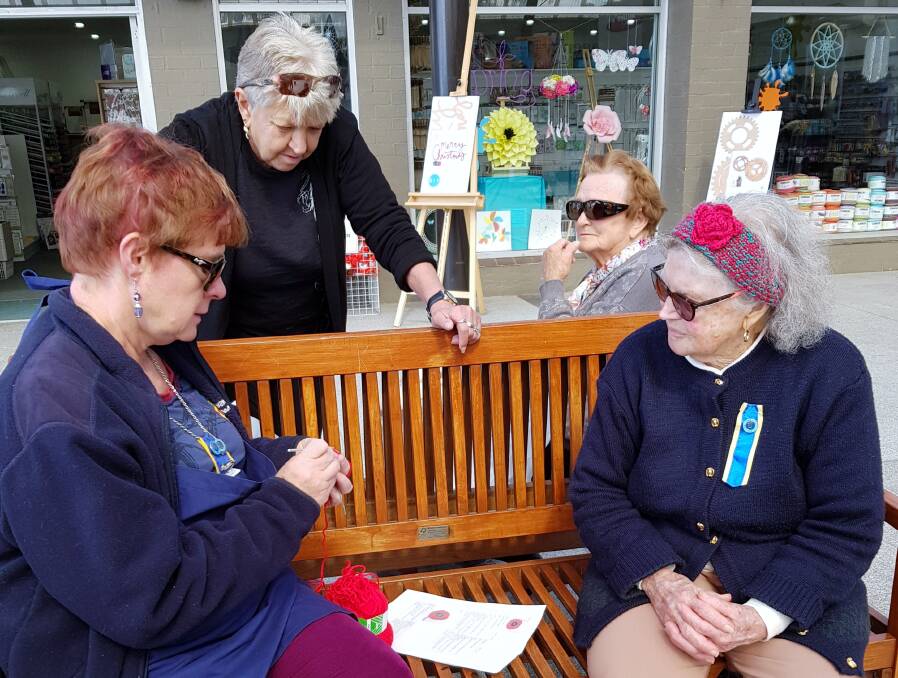 DAB HAND: Narooma CWA member Sally James demonstrates how to crochet poppies for Enid Gorton and onlookers.

