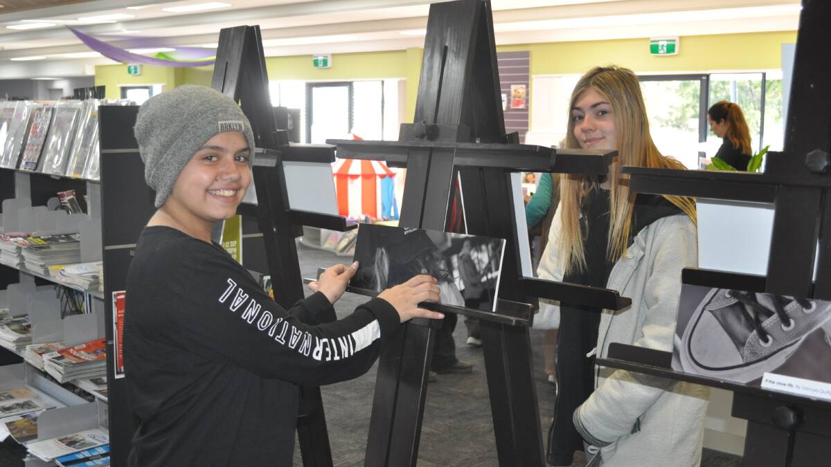 Narooma High School students Sahnyia Dufty-Terare and Shannon Carles arrange photographs for their exhibition at Narooma Library. It runs until Friday, August 31.