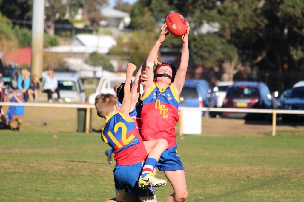 Reaching heights: Narooma's Will Tiffen takes a contested mark in a match against the Merimbula Diggers. Image: Kim Harris. 