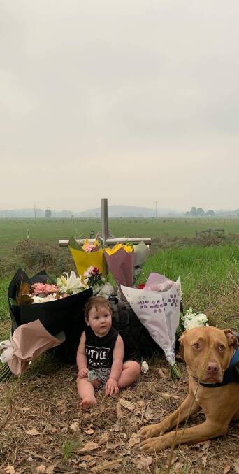 Jase Taylor sits with Zoula the dog at his father's roadside memorial on Sunday, February 2. 