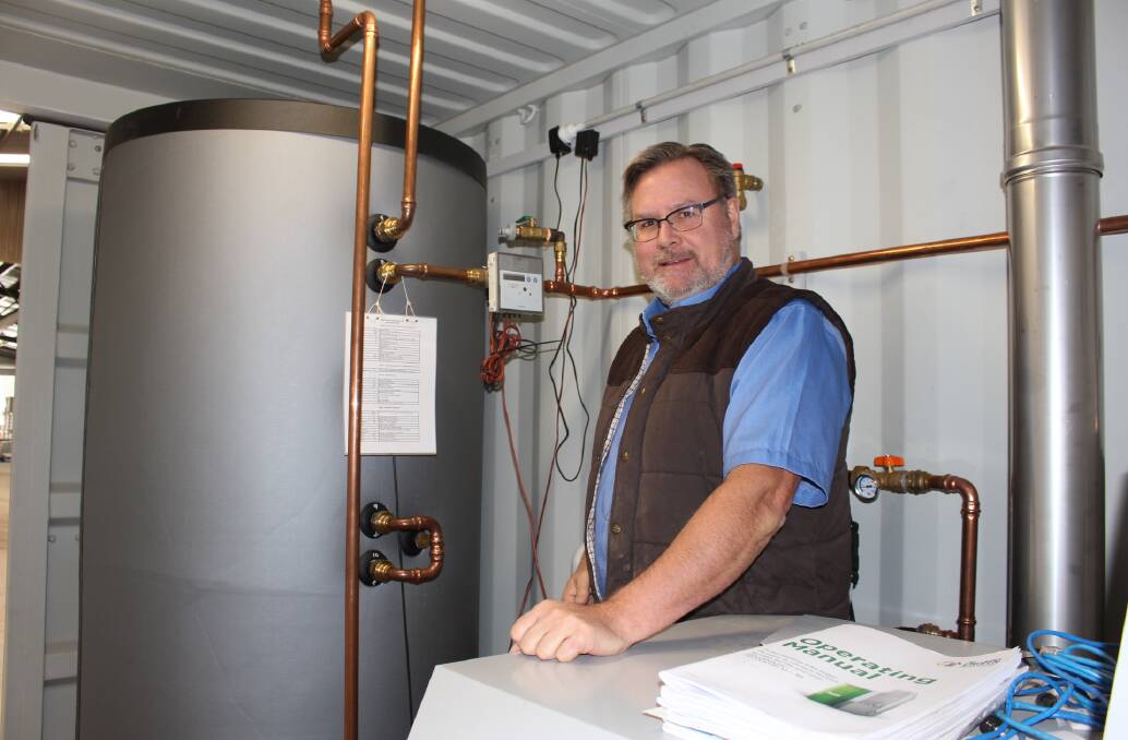Tony Esplin of RTG inside the Dairy Cube next to the hot water storage and heating system.