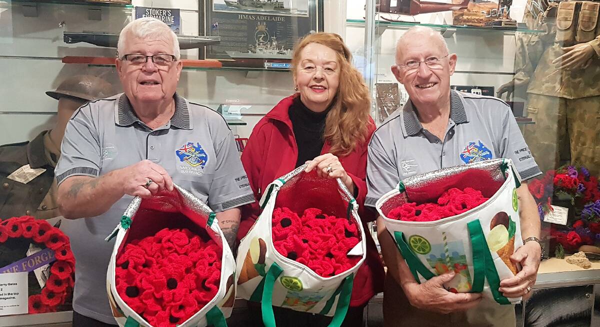 DARN FINE: Paul Naylor, Joan Bolan, and Jon King with 400 memorial poppies hand-knitted by Ms Bolan and destined for Canberra's War Memorial.