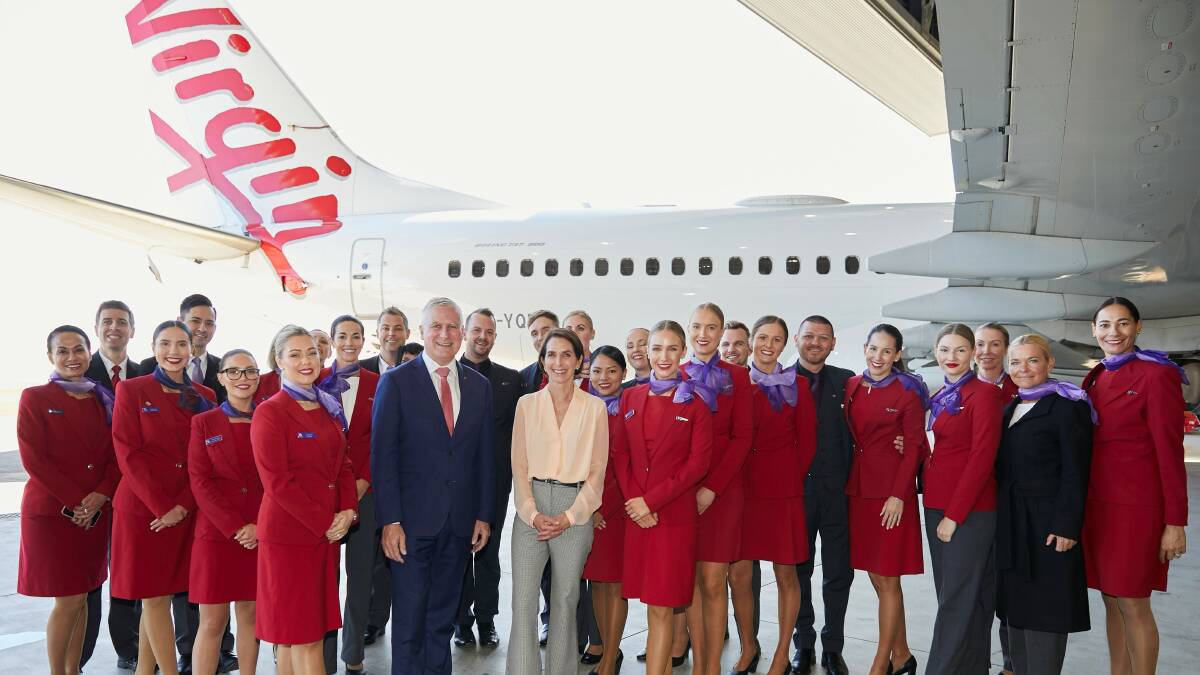 Virgin Australia staff stand in front of a Virgin Australia aircraft.
