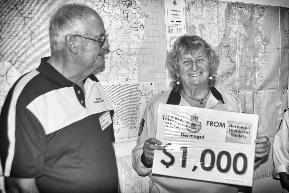 Maggie McKinney, president of Bermagui RFS, receives the cheque from Allan Douch, president of Bermagui Historical Society.