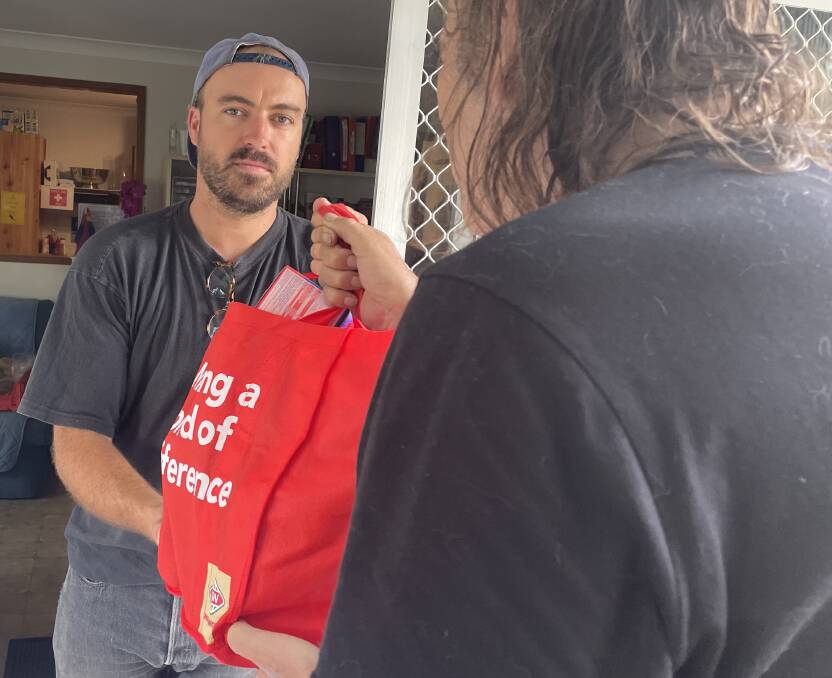 SUPPORT: Shoalhaven Homeless Hub caseworker Joey Winkler hands out a food supply bag to a client.