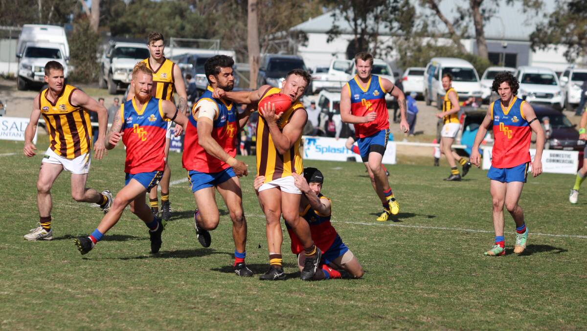 Man of the match: Pambula's Aaron Proctor fends off a tackle attempt from two of the Narooma Lions during the senior grand final. 