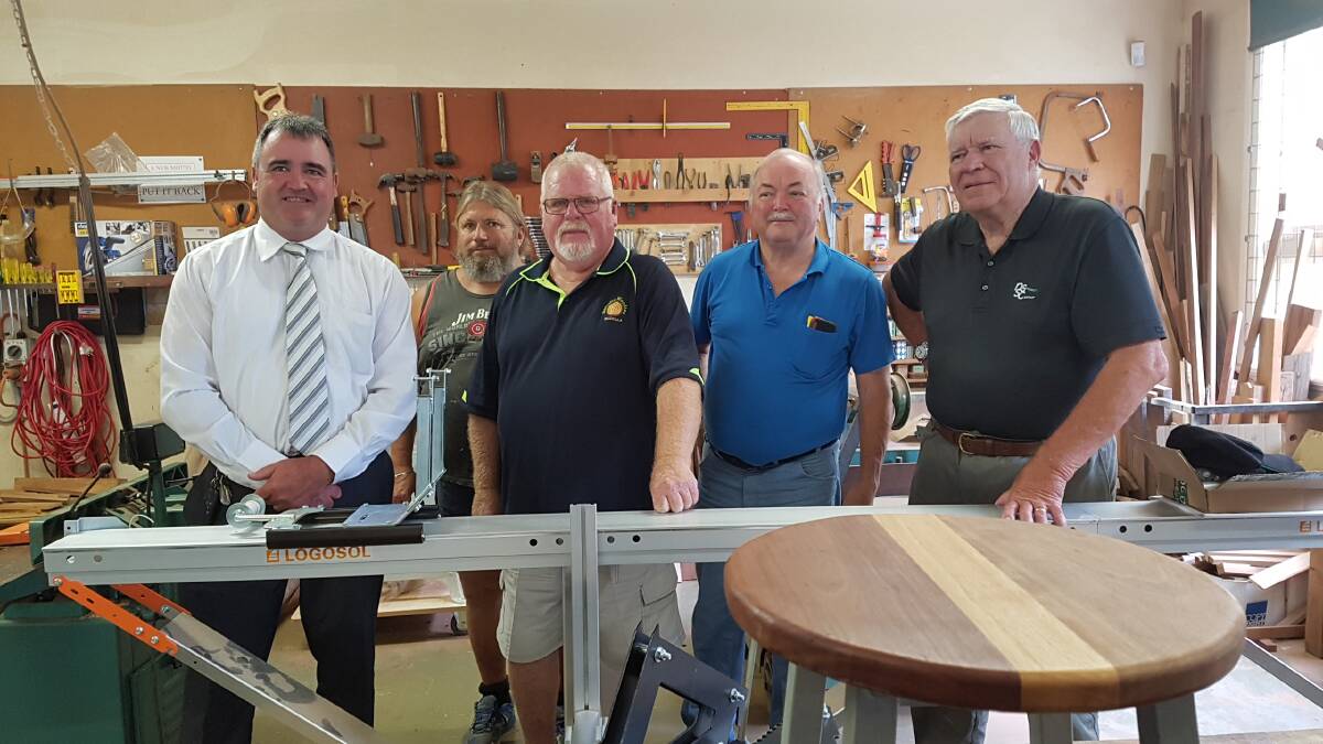 NEW MILL: Narooma Sporting & Services Club general manager Tony Casu and president Graham Reeve with the Narooma Woodies inspecting the new portable timber mill they donated at a cost of $4800.  