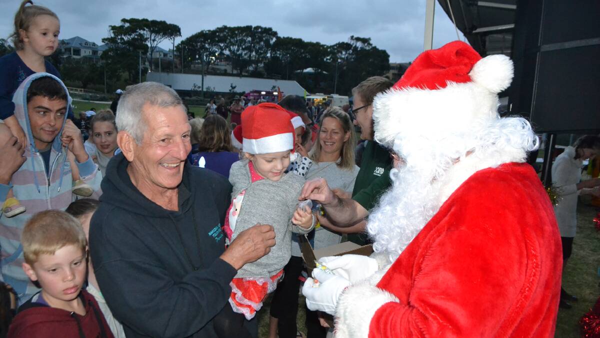 Excited children greet Santa on his arrival at the 2016 Narooma Carols by Candlelight event. 