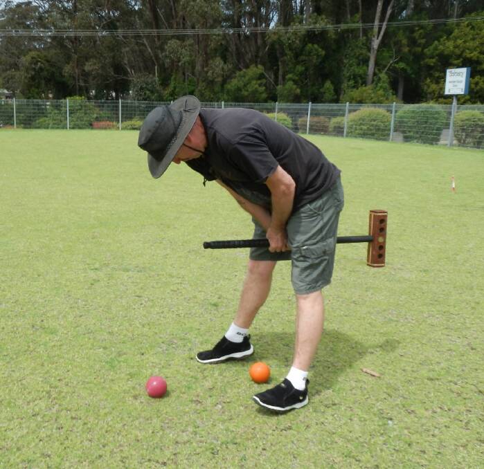 Croquet player Brian Mitchell from Nowra demonstrates the technique of playing a jump shot during a game at the Club Dalmeny croquet courts.