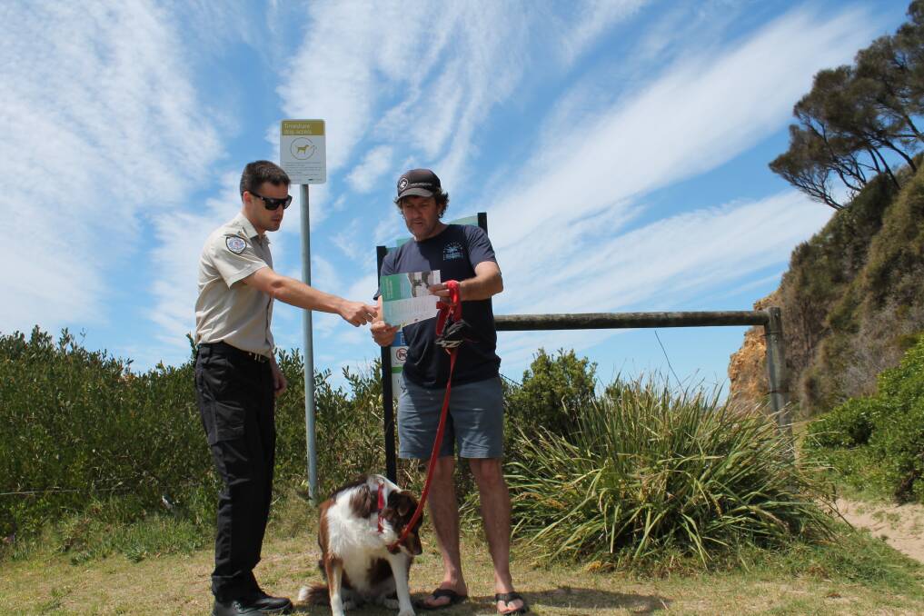 Eurobodalla Shire ranger Mitchell Stirling explains new timeshare arrangements to a dog owner. Changes to timeshare beaches in the shire come into effect from November 1.