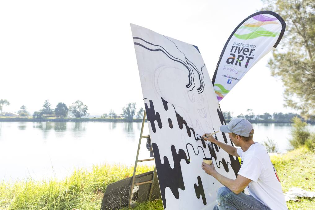 POSITIVE ENERGY: Happy Decay (Bjarni Wark) paints beside the Moruya River during the 2019 festival. This year, the artist will paint a mural in Batemans Bay on the corner of North and Perry Streets.
