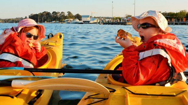 Emily and Sarah tuck into pizza in their kayaks under the Batemans Bay Bridge. Photo: Tim the Yowie Man

