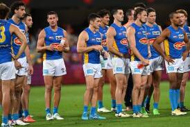 Gold Coast Suns players reflect on defeat after their clash with the Brisbane Lions at the Gabba. (Darren England/AAP PHOTOS)