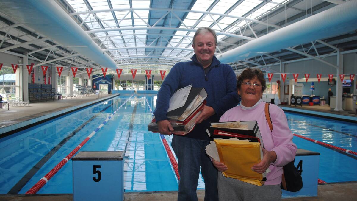 POOLSIDE: Councillor Neil Burnside with Patricia Eaton studying the archives at the YMCA Narooma Swimming Centre. 