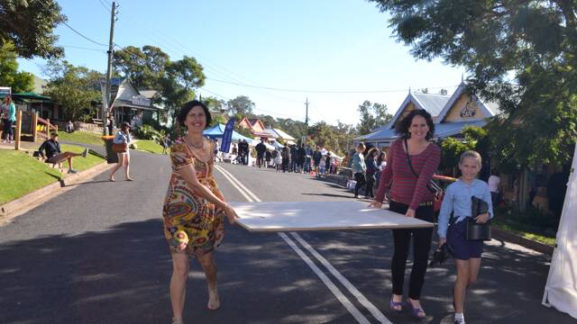 DANCE PLATFORM: Carrying the wooden platform for young tap dancer Lillian McVeity at the Tilba Festival on Easter Saturday are Layla Oster from the Reva shop and mum Candy.