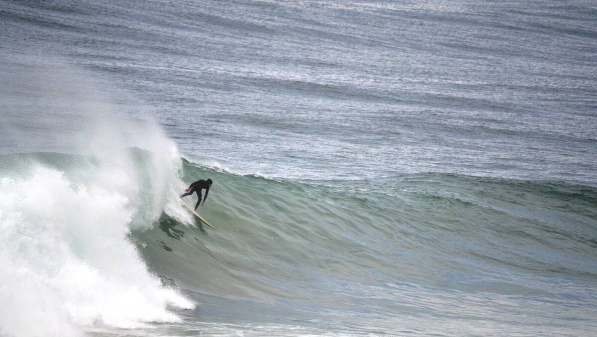 Surfers inlcuding Benjamin Safari ride the big swell at Narooma 